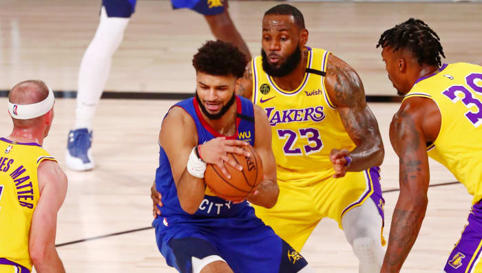 Denver Nuggets guard Jamal Murray (27) holds the ball while defended by Los Angeles Lakers guard Alex Caruso (left) forward LeBron James (center) and center Dwight Howard (right) during the second quarter